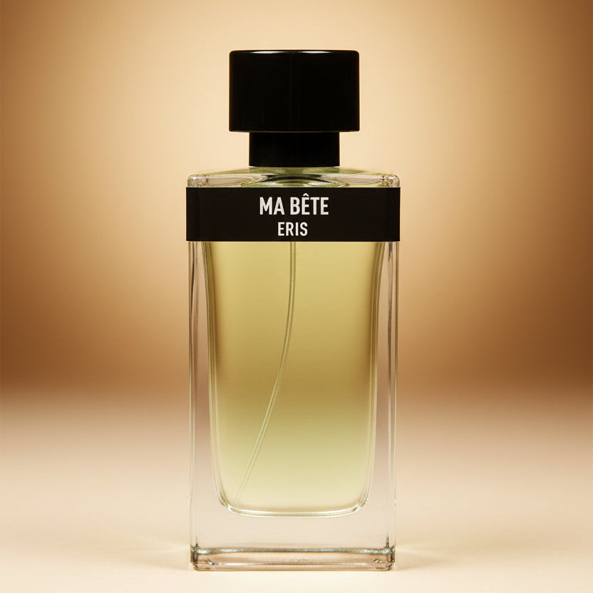 Tall rectangular perfume bottle filled with amber liquid with a round black cap, a black band around the top of the bottle body that says "Ma Bete ERIS" on it set against a warm gradient background. 