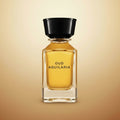 A clear glass perfume bottle filled with golden-yellow liquid, featuring a black cap and the text 'OUD AQUILARIA' on the front, set against a white background with a soft shadow.